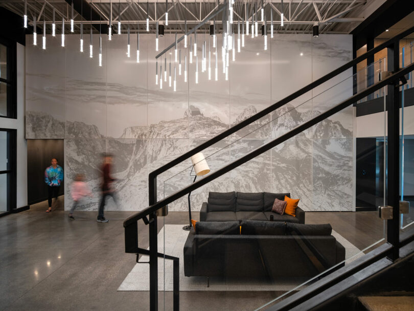 Interior of a modern building featuring a large mountain mural and a striking black metal staircase.