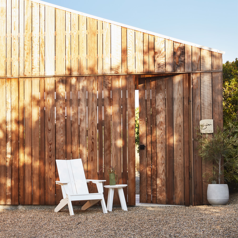 Modern outdoor furniture set including chairs and a fire pit arranged for an autumn evening in a manicured garden.