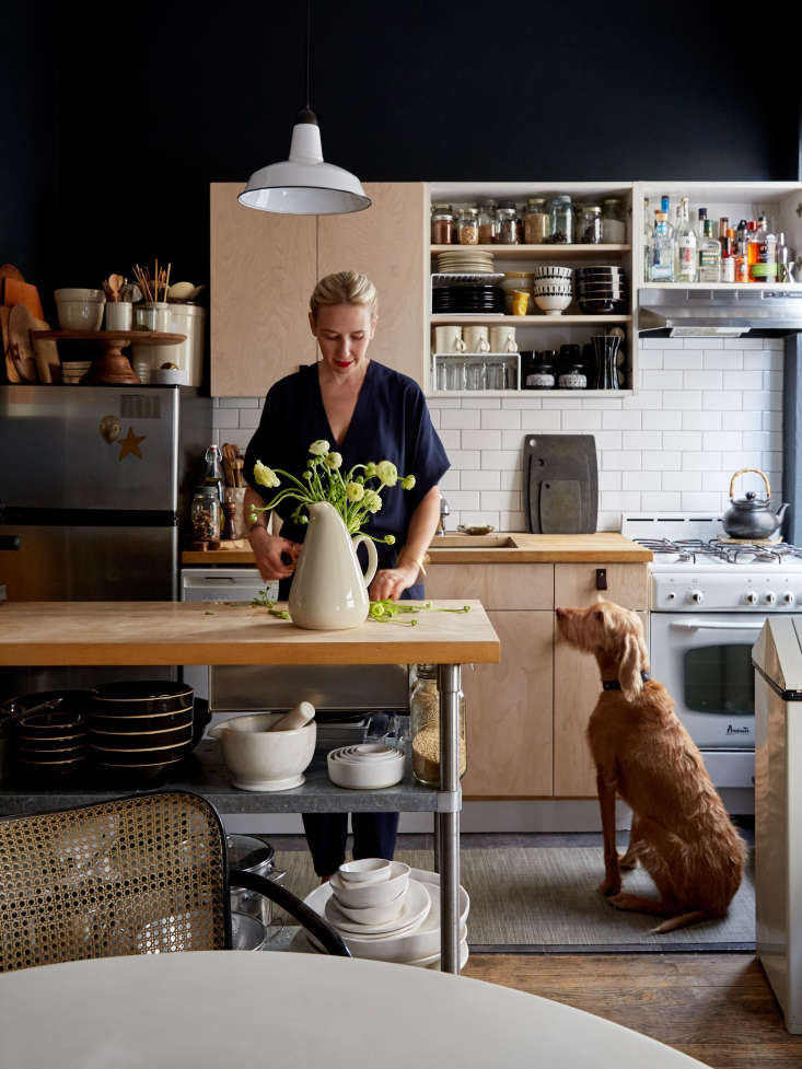A small single-wall kitchen with a wooden mobile island in the center providing extra prep surface.