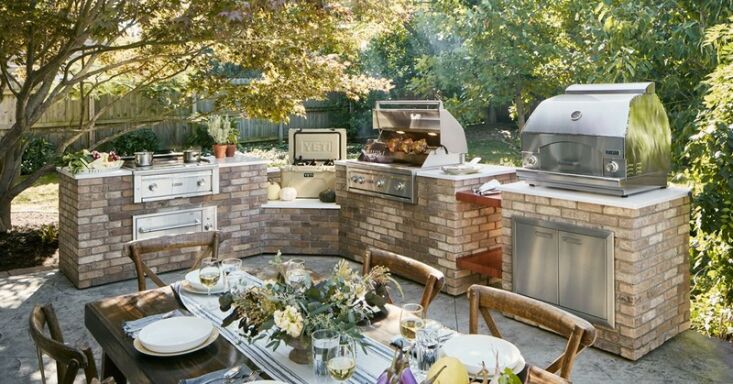 An expansive L-shaped outdoor kitchen with a built-in grill and a bar-style seating area.