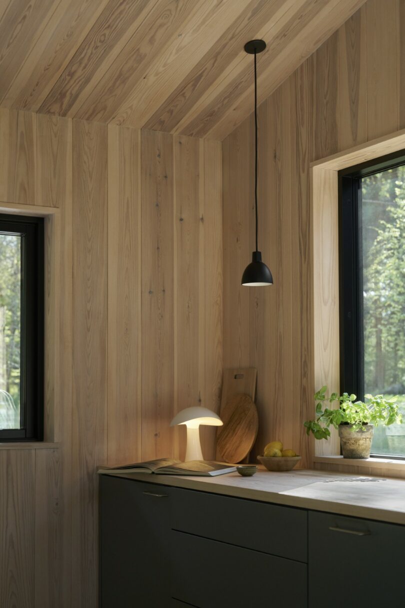 A glowing table lamp on a kitchen counter with wood-paneled walls and dark cabinets.