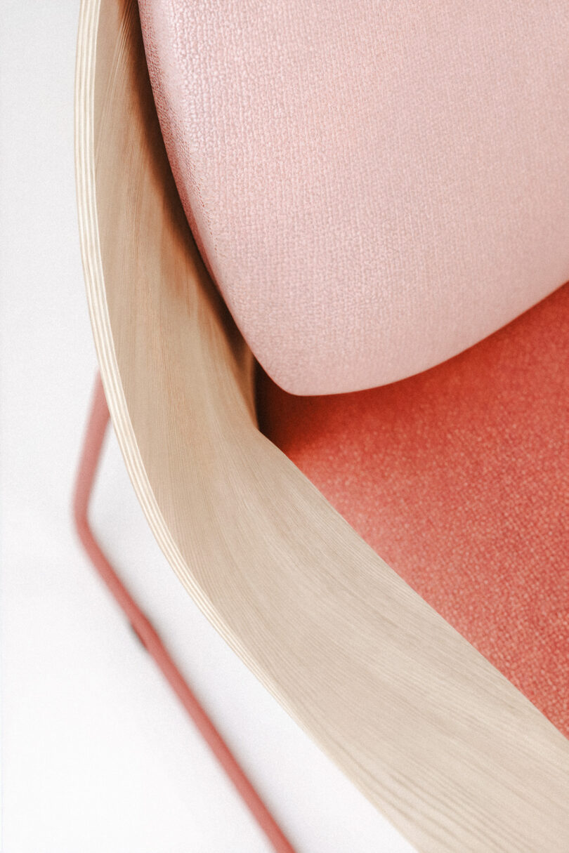 Close-up of the Mysa chair featuring the intersection of the light wood frame and pink fabric backrest.